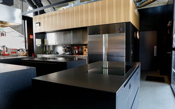 Moderne Küche mit Kühlschränken, Arbeitsflächen und Geräten.